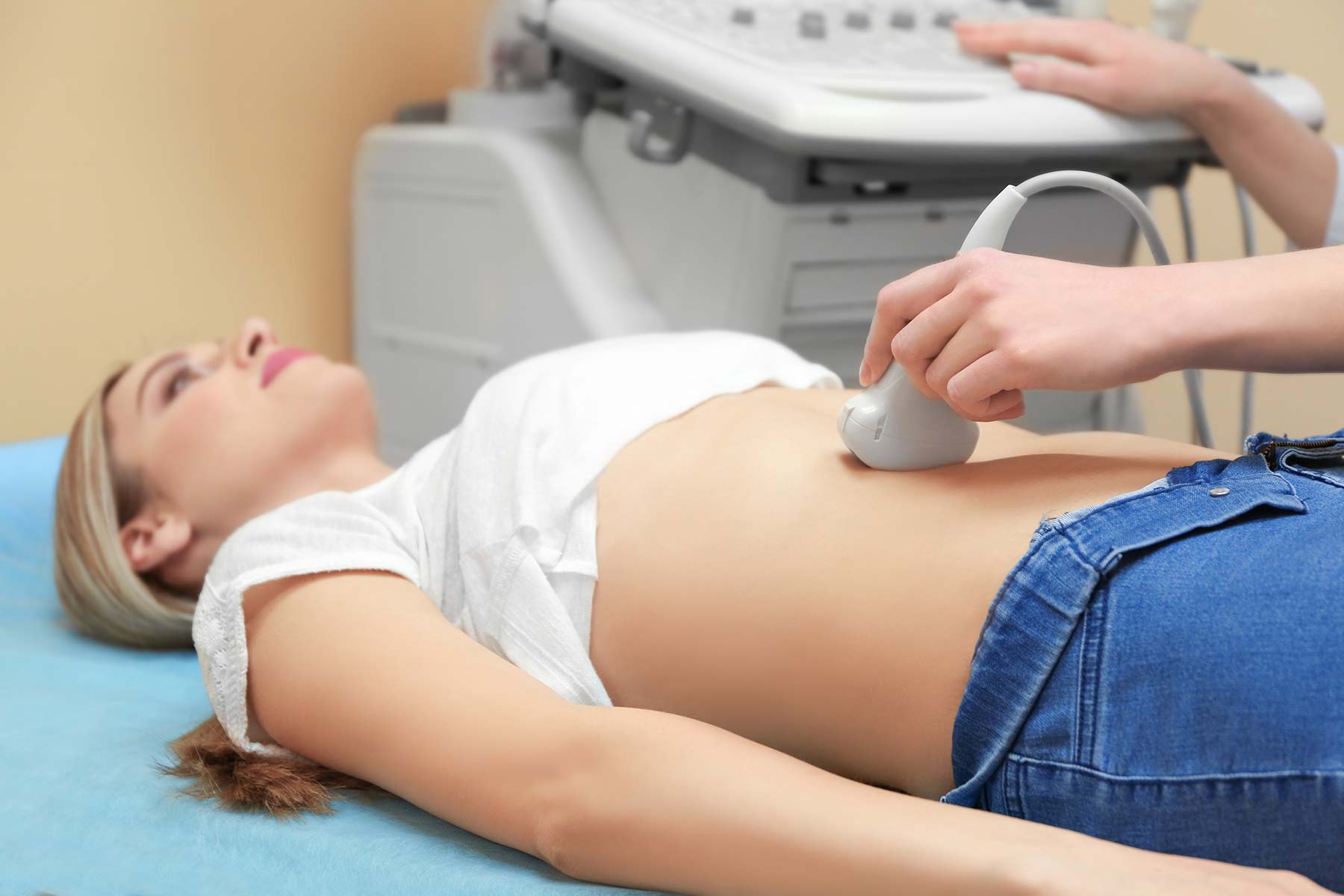 A patient lying down as a doctor performs an abdominal ultrasound scan in a clinic A patient lying down as a doctor performs an abdominal ultrasound scan in a clinic
